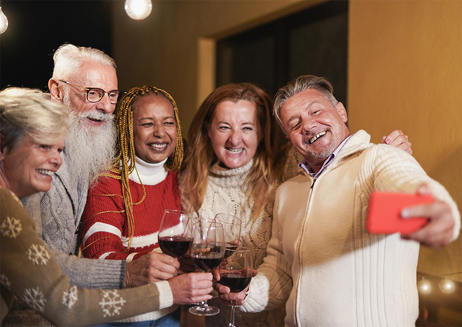 Amis seniors multiraciaux applaudissant avec du vin rouge tout en prenant un selfie - Personnes âgées célébrant les fêtes