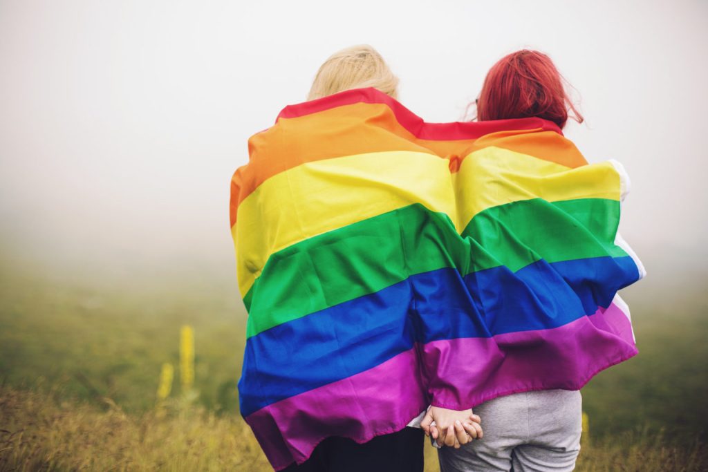 Two people holding closely under rainbow flag