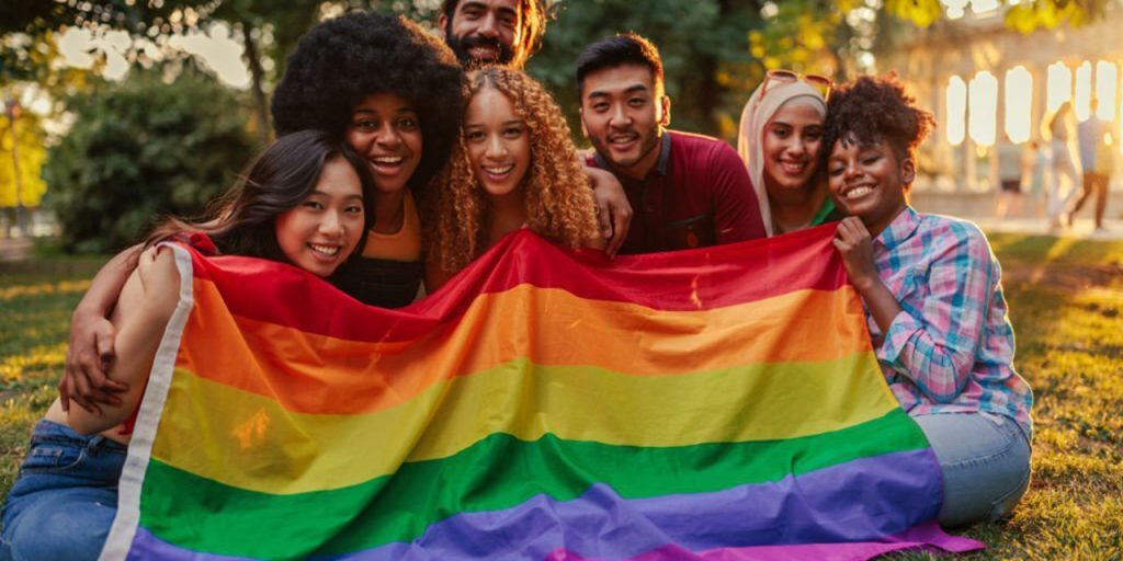 Diverse group of youth with rainbow flag in park
