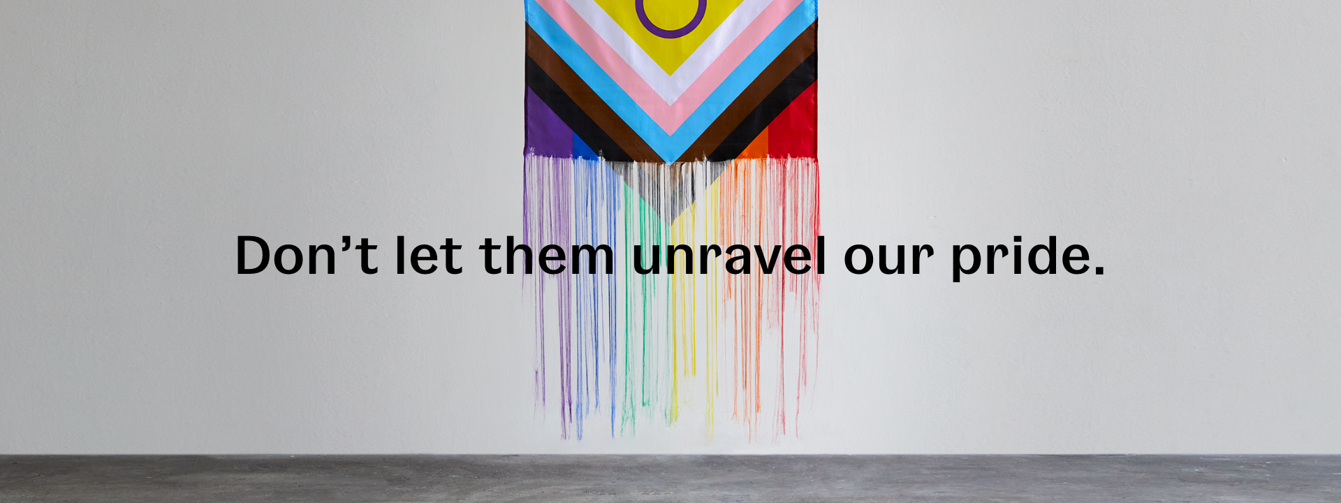 Don't let them unravel our pride. (Progress pride flag hanging vertically with threads unravelling.