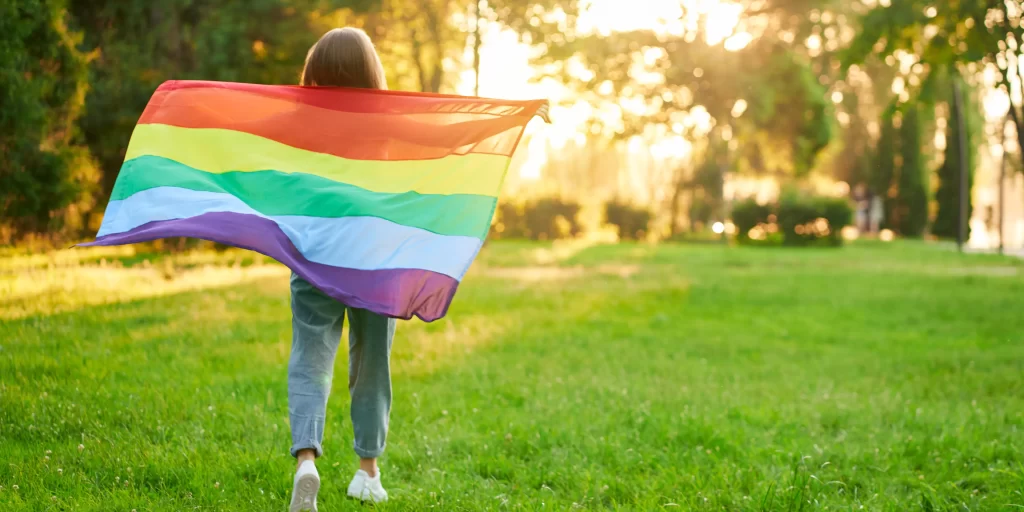 Girl enjoying sunset holding rainbow flag
